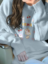 Light gray sweater with colorful graphics and text worn by a person.